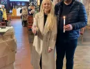 Jack and Georgie standing by the font in St. Sabinus' church with members of the congregation in the background.  Both are holding lit baptism candles